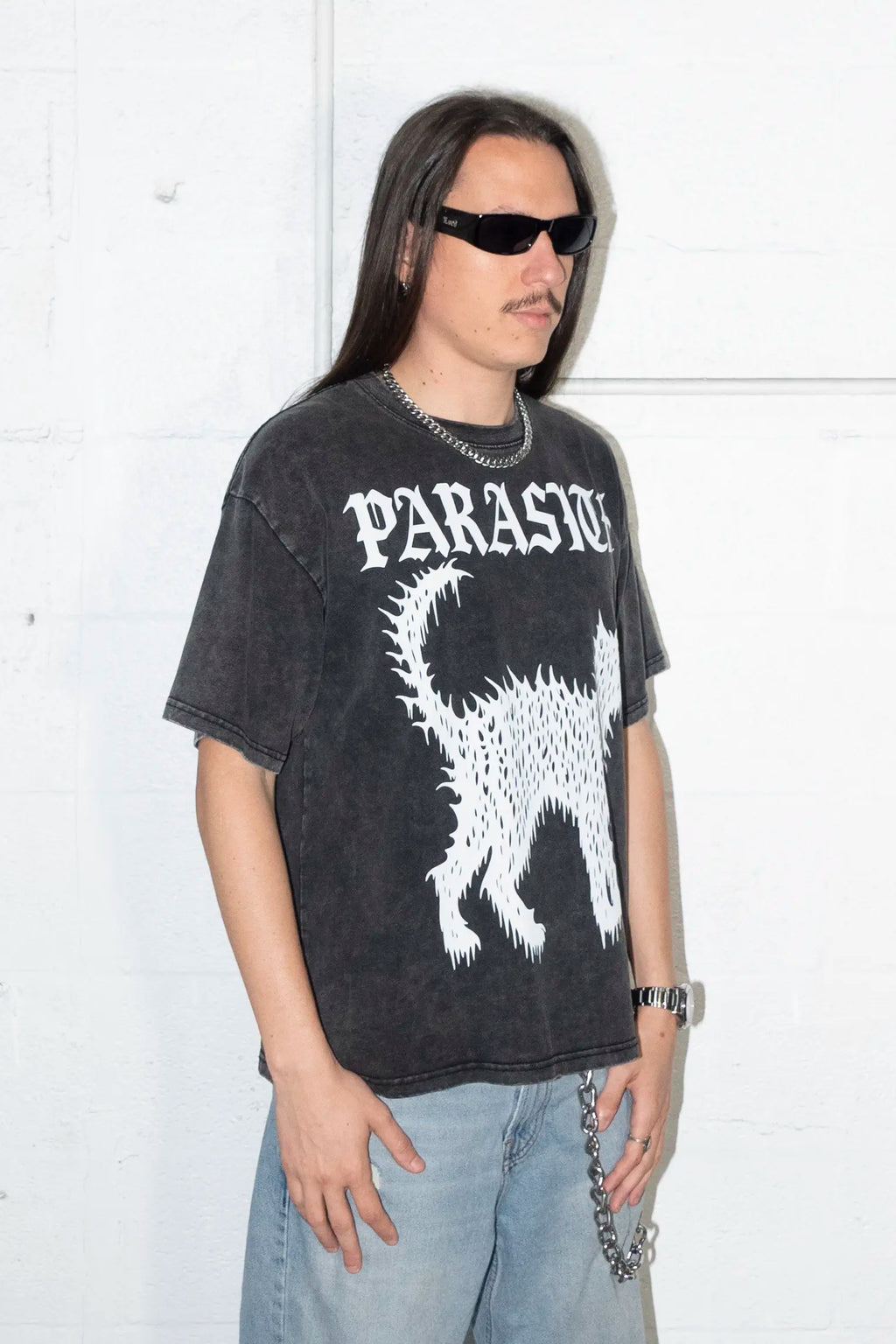 Person wearing a black t-shirt with Parasite Label text and Slime Cat  graphic design against a white background