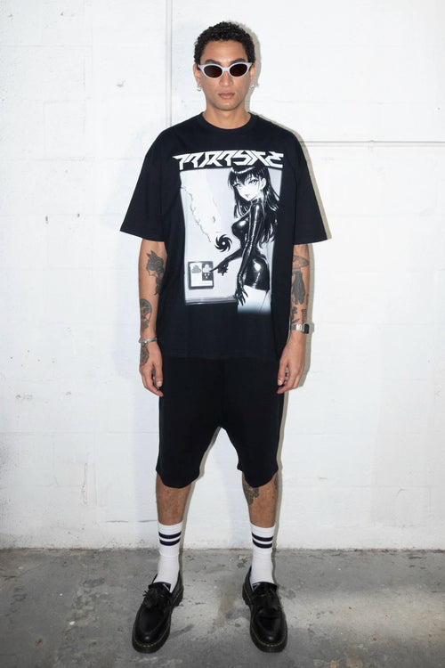 Person wearing a black t-shirt with a Parasite Label graphic design and text, standing against a white background black shorts, and black shoes against a white wall.