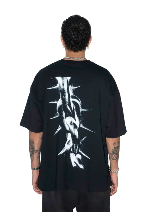 Person wearing a black t-shirt with a white spike chain link graphic design on the back, standing against a white background.