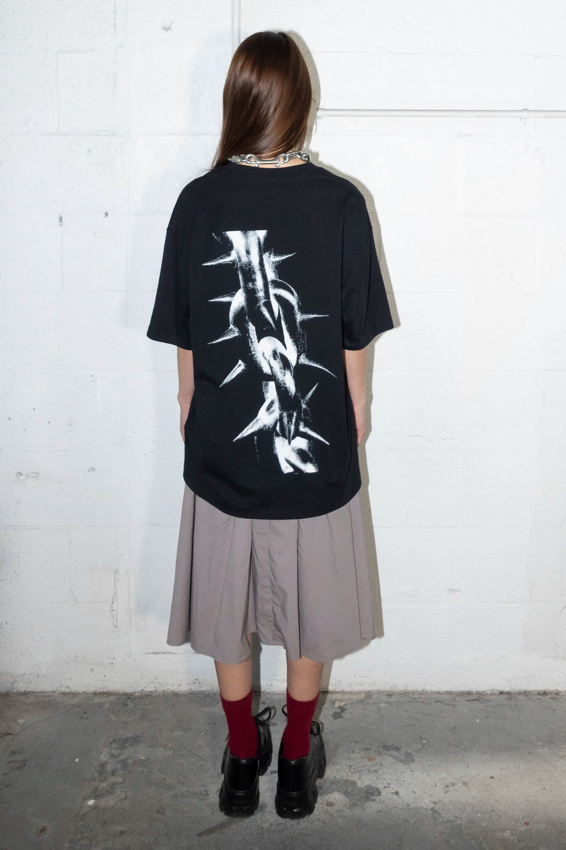 Person wearing a black t-shirt with white spike chain link graphic design 