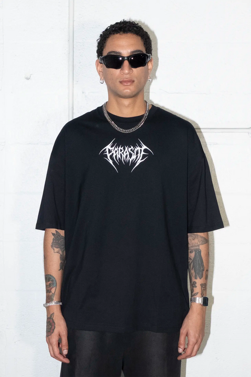 Person wearing a black t-shirt with a Parasite Label logo, standing against a white background