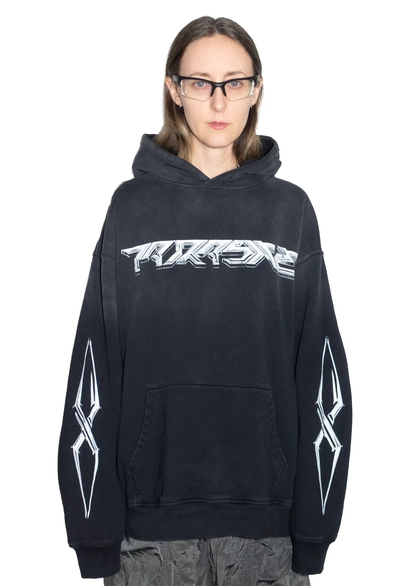 Person wearing a black hoodie with white chrome 3d Parasite Label graphics on a white background