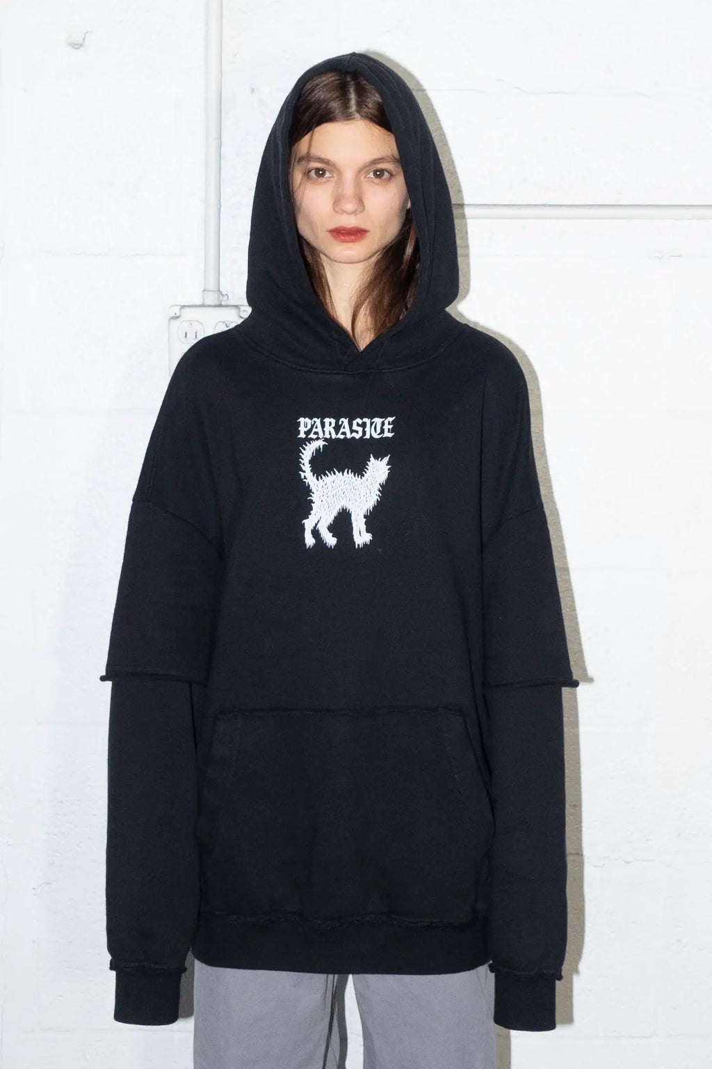 Person wearing a black hoodie with a white cat logo and Parasite Label text on a white background