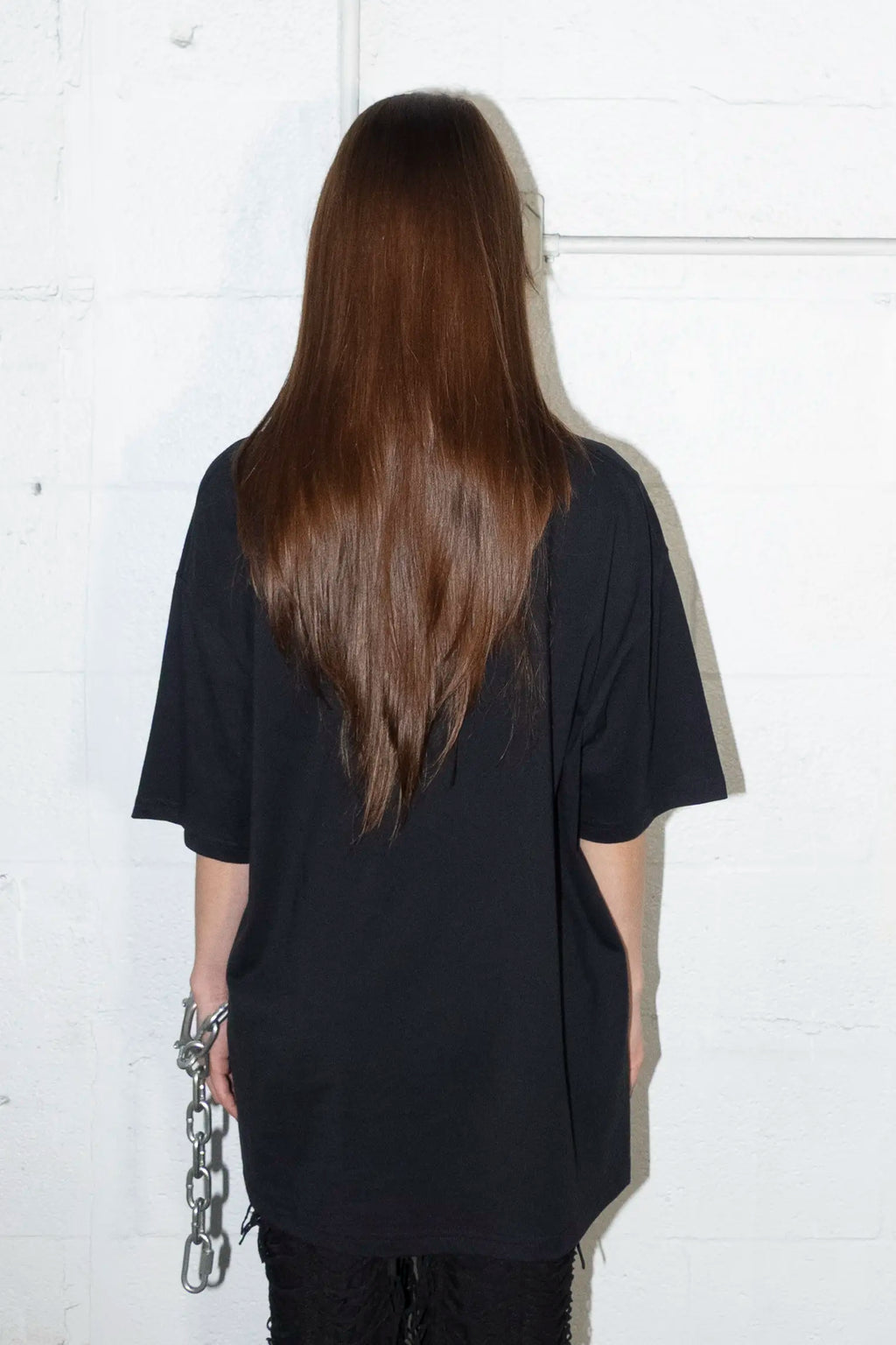 Person wearing a black oversized t-shirt against a white background